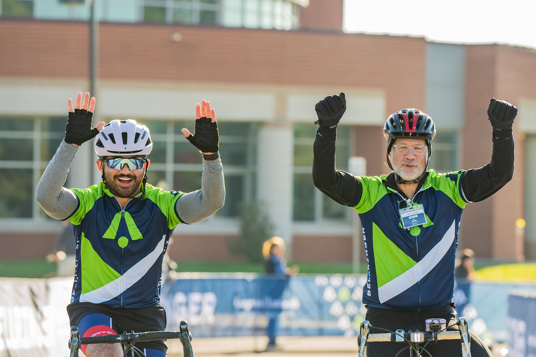 Two BellRinger riders celebrating as they ride their bikes across the finish line