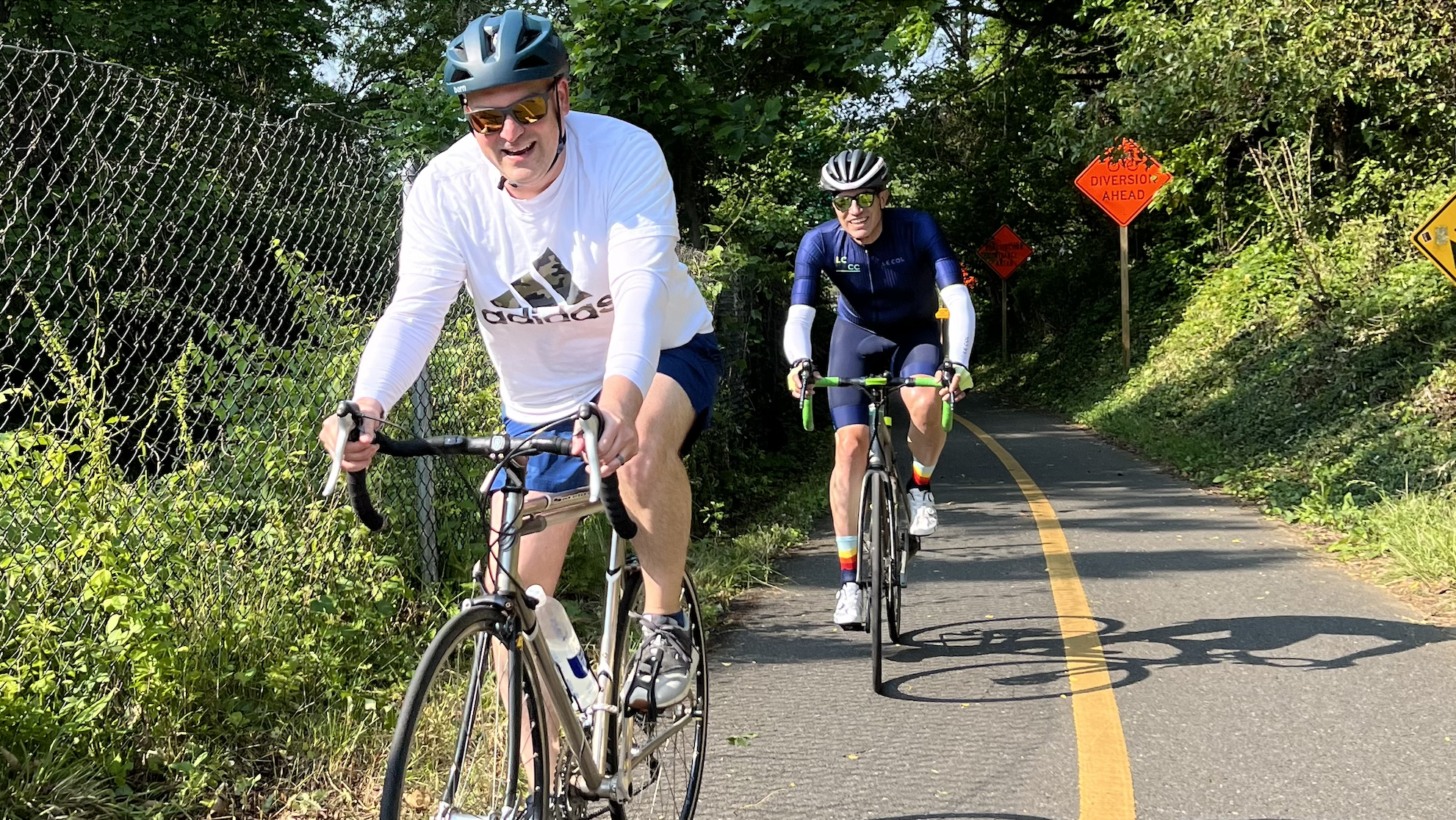 Two BellRinger riders biking on a bike path with trees