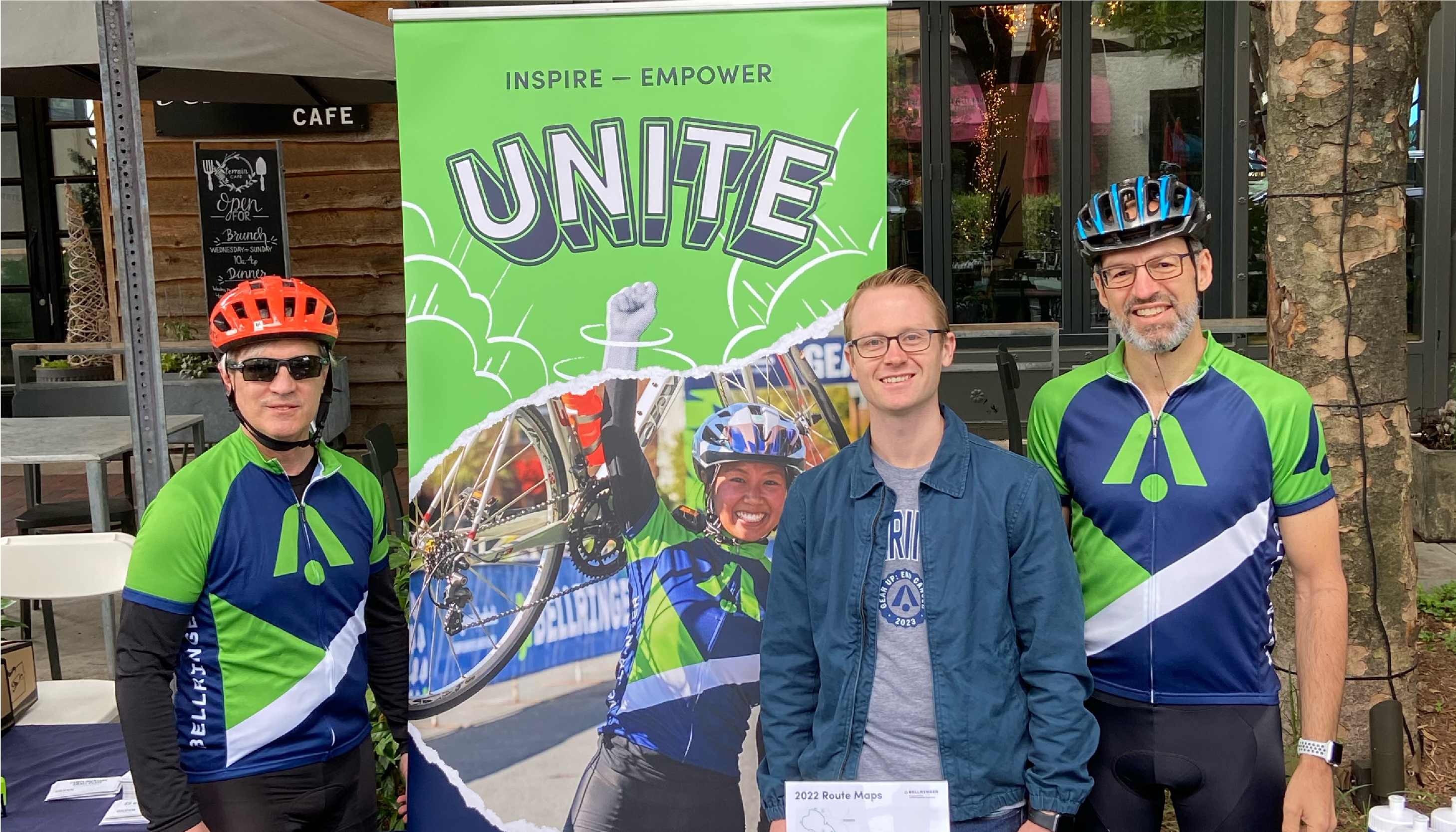 Three BellRinger riders posing in front of a inspire empower unite sign
